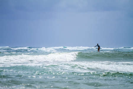 Lihue, Kauai, USA - 10 April, 2012: Stand up paddle surfing off of Kapa'a Beach during the daytime