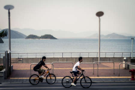 Hong Kong, China - 15 April, 2011: Tilt shift image of cyclists riding along the Tolo Harbour recreational path in the New Territoriesのeditorial素材