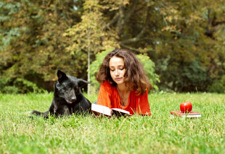 The girl and dog lying on a grass in parkの写真素材