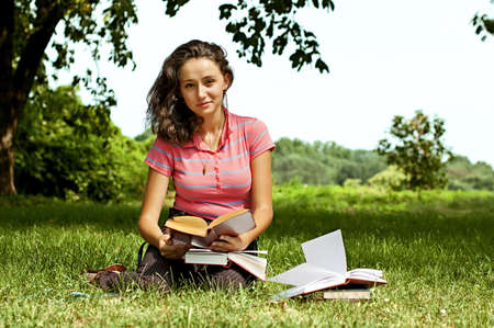 The girl sitting on a grass, reading a bookの写真素材