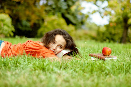 The girl with books lying on a grassの写真素材