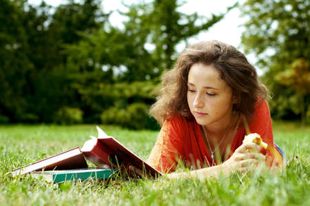 The girl with books lying on a grassの写真素材