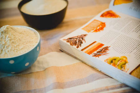 flour, eggs, foam egg whites, egg beater, rolling pin and egg shells on wooden tableの写真素材