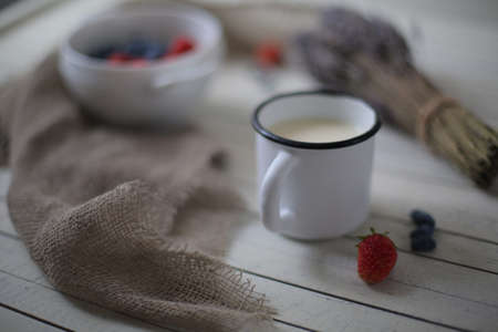 oatmeal porridge, bottle of milk and berries on wooden background with kitchen towel, top viewの写真素材