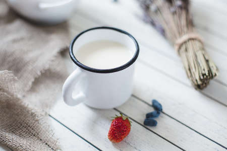oatmeal porridge, bottle of milk and berries on wooden background with kitchen towel, top viewの写真素材