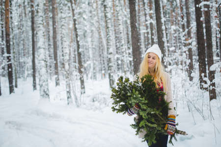 girl in winter forest keeps the fir-tree branches in his handsの写真素材