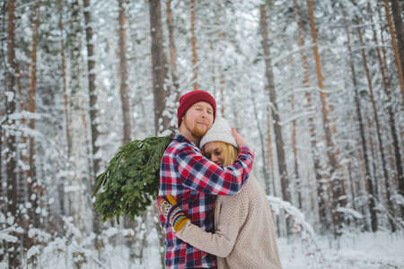 young couple in a plaid shirt with fir twigs walk in the winter woodsの写真素材