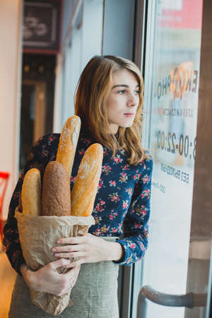 woman holding baguettes of bread in his handの写真素材