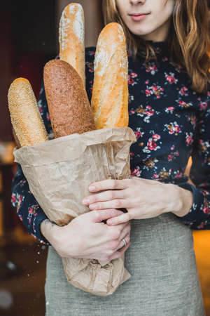 woman holding baguettes of bread in his hand