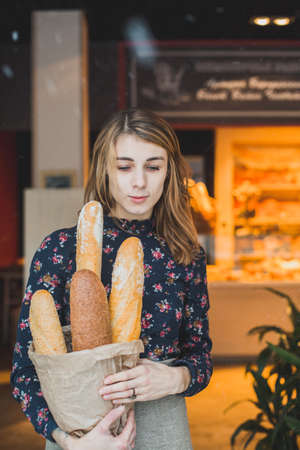 woman holding baguettes of bread in his hand