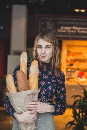woman holding baguettes of bread in his handの写真素材