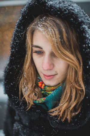 Cute young woman playing with snow in fur coat outdoorsの写真素材