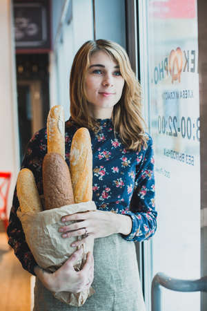 woman holding baguettes of bread in his handの写真素材