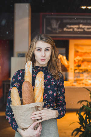 woman holding baguettes of bread in his handの写真素材