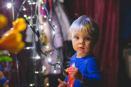 the little boy with the twinkle lights near the mirror