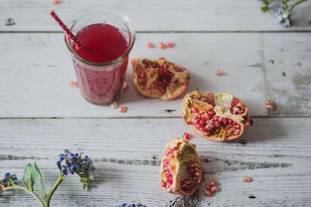 glass of pomegranate juice with fresh fruits on wooden tableの写真素材