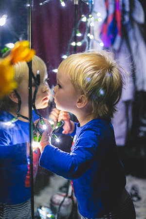 the little boy with the twinkle lights near the mirrorの写真素材
