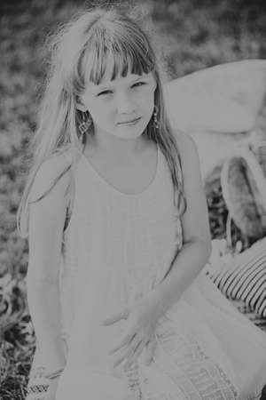 young teen girl sitting and smiling on a blanket in natureの写真素材