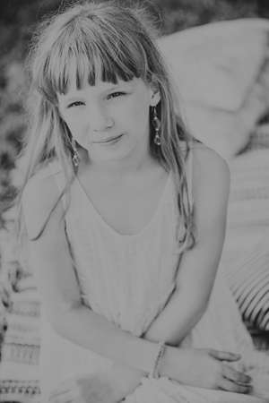 young teen girl sitting and smiling on a blanket in natureの写真素材
