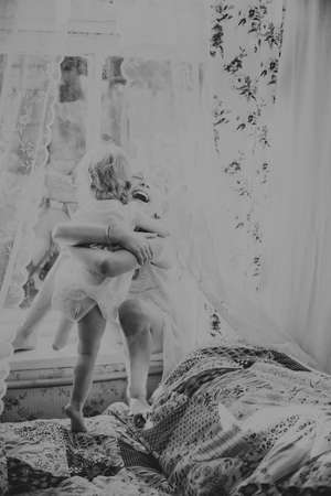 two sisters playing near the window in the afternoonの写真素材