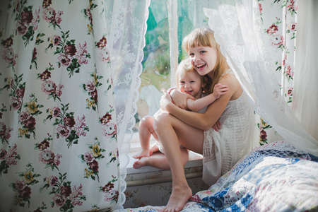 two sisters playing near the window in the afternoonの写真素材