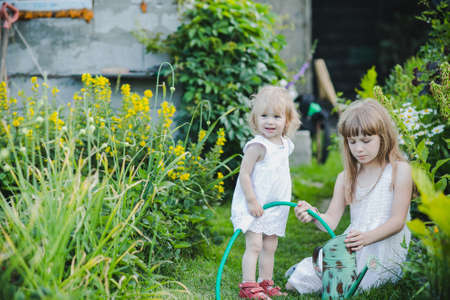 two sisters are some of the beautiful flowers with a watering canの写真素材