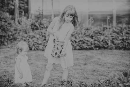 two sisters are some of the beautiful flowers with a watering canの写真素材