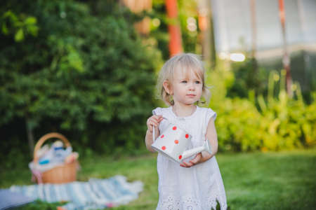 Little baby girl standing among beautiful violent flowers, summer portraitの写真素材