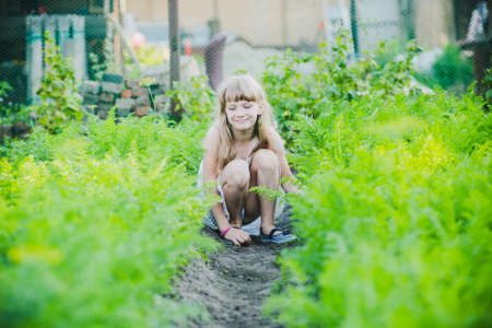 beautiful little girl standing with a watering can in the gardenの写真素材