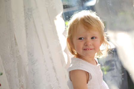 Baby girl looking through the window. Toddlers fantasy and dreams.の写真素材