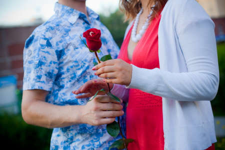 man and woman standing and holding a flower embracingの写真素材