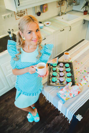 young blond woman drinking tea in the kitchenの写真素材
