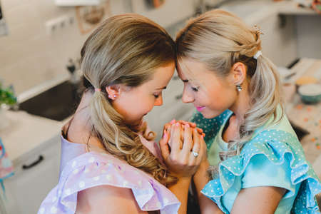 two happy women arm in arm in the kitchenの写真素材