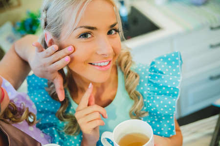two women in kitchen drinking a cup of teaの写真素材
