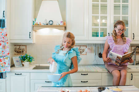 two women in the kitchen preparing food.の写真素材