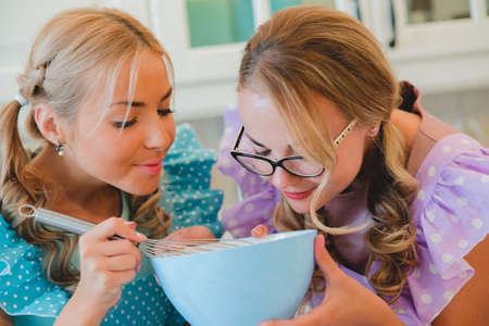 two women in the kitchen preparing food.の写真素材