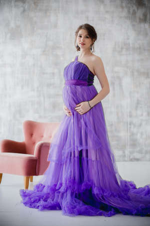 beautiful pregnant woman posing in purple dress in Studioの写真素材