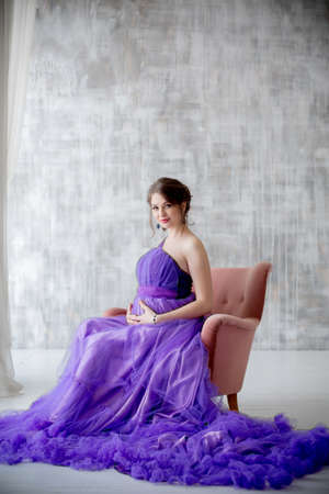 beautiful pregnant woman posing in purple dress in Studioの写真素材