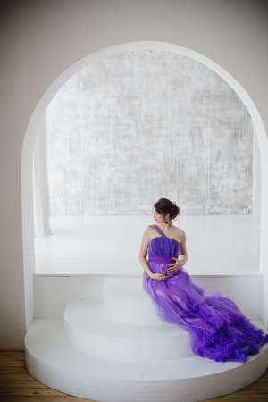 beautiful pregnant woman posing in purple dress in Studioの写真素材