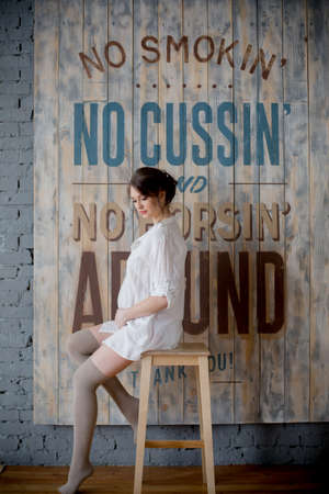Portrait of a young pregnant woman in white shirt in photo Studioの写真素材