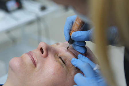 Permanent makeup. Permanent tattooing of eyebrows. Cosmetologist applying permanent make up on eyebrows- eyebrow tattooの写真素材