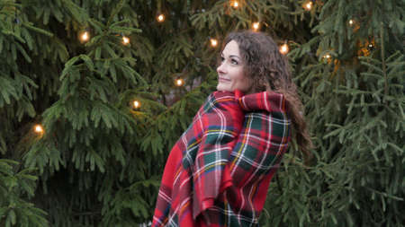 young woman in a plaid against a christmas tree background and garlandsの写真素材