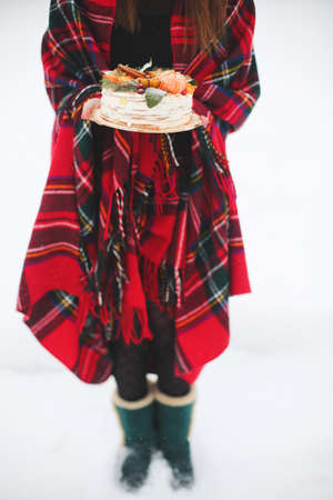 young woman holding a christmas cake in the street. its snowing, sparklerの写真素材