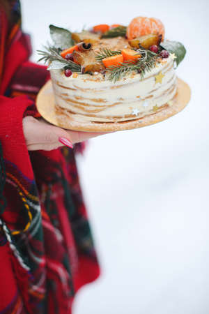 young woman holding a christmas cake in the street. its snowing, sparklerの写真素材