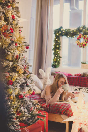 young woman in christmas interior. Sit with a plaid and a cup of tea.の写真素材