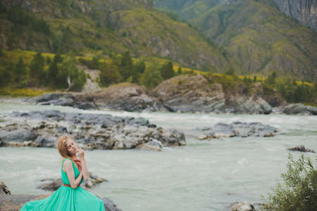 young woman in a long flowing dress on the background of the river and mountains. coloring women...