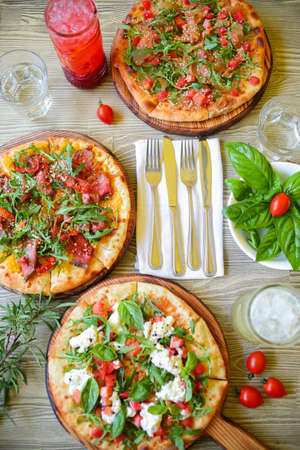 Raw pizza. Rolled out dough on a cutting Board with tomato paste, mozzarella and spinach. On rustic backgroundの写真素材