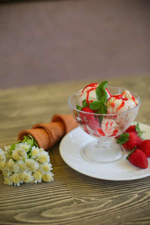 Delicious strawberry ice cream scoop with fresh strawberries on wooden backgroundの写真素材
