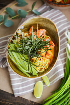 Bowl of stir fried udon noodles garnished with black sesame seeds and fresh mint with green chopsticks.の写真素材