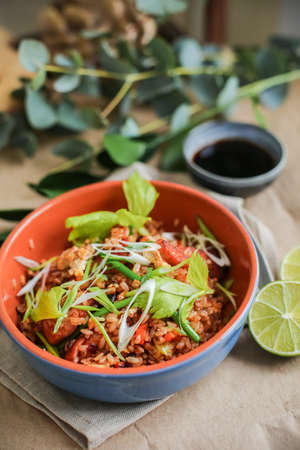 Bowl of stir fried udon noodles garnished with black sesame seeds and fresh mint with green chopsticks.の写真素材